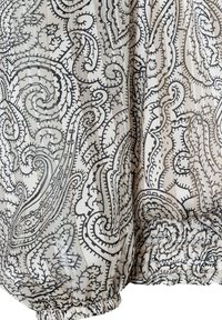 Lekki materiał z misternym czarnym wzorem paisley na kremowym tle. Posiada marszczony dół i subtelne akcenty w złotym ściegu.