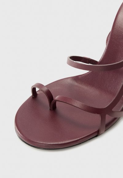 Šedo-fialové ploché sandály s dvěma tenkými pásky přes prsty a jedním páskem na kotníku. Vyrobené z hladké umělé kůže s minimalistickým designem.