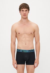 Zwarte boxershorts met een elastische tailleband en een blauw-groene gradient "NIKE" logo. Gladde stof, slim-fit ontwerp, lengte tot halverwege de bovenbenen.