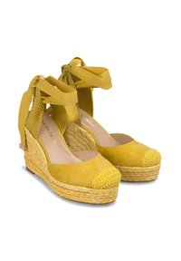 Scarpe con zeppa gialla in suede, suole in juta intrecciata, punta arrotondata e cinturini alla caviglia. Il tessuto testurizzato vicino al tallone arricchisce il dettaglio del design.
