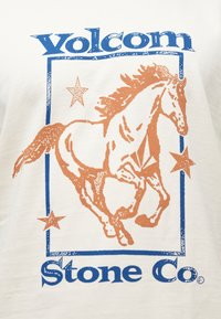 Λευκό βαμβακερό μπλουζάκι με σχέδιο μπλε και πορτοκαλί που απεικονίζει ένα τρέχον άλογο, περικλειόμενο από αστέρια και το κείμενο "Volcom Stone Co".