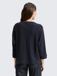 Navy blue, textured, loose-fitting sweater with three-quarter sleeves and a boat neckline, featuring a straight back hemline.
