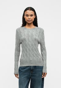 Grauer Strickpullover mit rundem Ausschnitt, langen Ärmeln, gerippten Bündchen und Saum; mit kleinem gesticktem Logo auf der Brust.