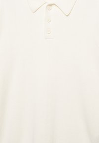 Helles Creme-Polohemd aus weichem Stoff mit klassischem Kragen und vier Knöpfen in der Mitte. Glatte Textur ohne Muster.