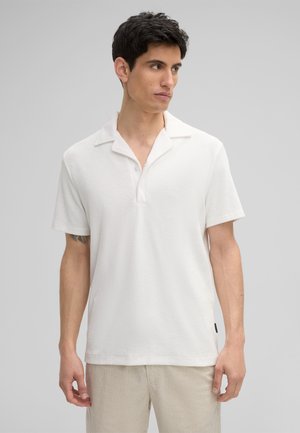 Weißes Kurzarm-Polohemd mit einer weichen Textur, einem Kragen und einer Knopfleiste mit drei Knöpfen, kombiniert mit hellgestreiften Hosen.