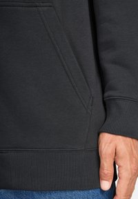 Schwarzer Sweatshirt-Stoff mit Seitentasche, geripptem Bund und Saum, mit glatter Textur und flachen Nahtdetails.