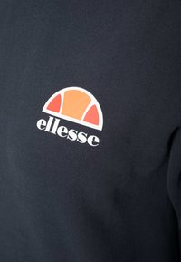 Felpa blu navy con un logo circolare con accenti arancioni e bianchi, che mostra "ellesse" in caratteri in grassetto sull'area sinistra del petto.