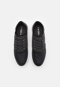 Une paire de baskets Lacoste Sport noires avec des semelles blanches, des capuchons de orteils en mesh, des lacets à motifs et un logo sur le côté, vues de dessus sur fond blanc.