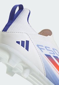 White athletic shoe featuring a textured upper, blue accents, and a low-profile design. Clear rubber outsole with multiple cleats for traction.