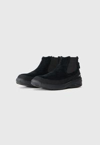 Las botas negras hasta el tobillo presentan un suave upper de ante y paneles laterales elásticos. Las suelas de goma ofrecen tracción, con una punta redondeada y acentos mínimos.