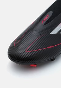 Black soccer cleat with ribbed texture, red accents on the upper, and "F50" branding. Features a pointed toe and a distinct sprinting design.