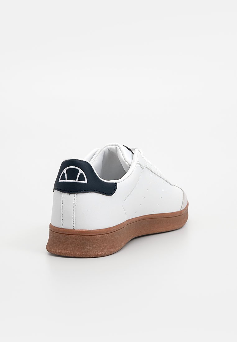 Zapatilla blanca con acento de cuero azul marino en el talón, suela de goma color crema, textura suave, perforaciones en los lados y logotipo bordado en el talón.
