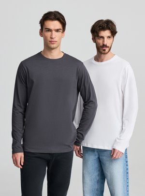 Due uomini indossano camicie a maniche lunghe, una di colore grigio scuro e l'altra bianca. Le camicie sono realizzate in tessuto liscio con scolli rotondi.