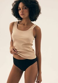 Beżowy prążkowany top na ramiączkach i czarne majtki z wysokim stanem; gładki materiał, dopasowany krój, szerokie ramiączka i okrągły dekolt.