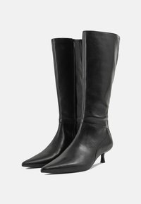 Black knee-high boots in smooth leather, featuring pointed toes, a low heel, and a side zipper for easy wear. Classic design with sleek lines.