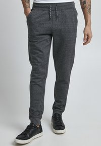 Dark gray sweatpants made of a soft material, featuring a drawstring waist, side pockets, and a tapered leg design.