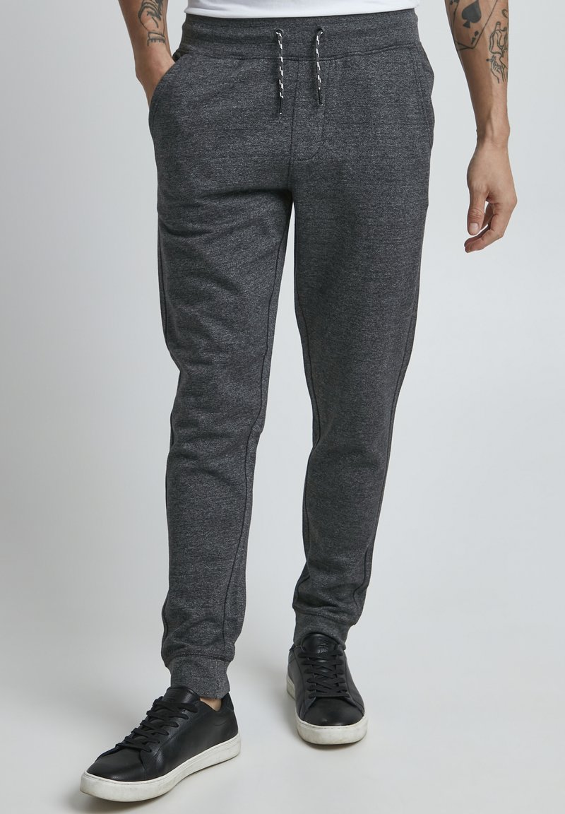 Dark gray sweatpants made of a soft material, featuring a drawstring waist, side pockets, and a tapered leg design.