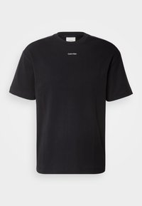 T-shirt en coton noir avec un col rond et des manches courtes. Présente un petit logo blanc "Calvin Klein" sur la poitrine. Design simple.