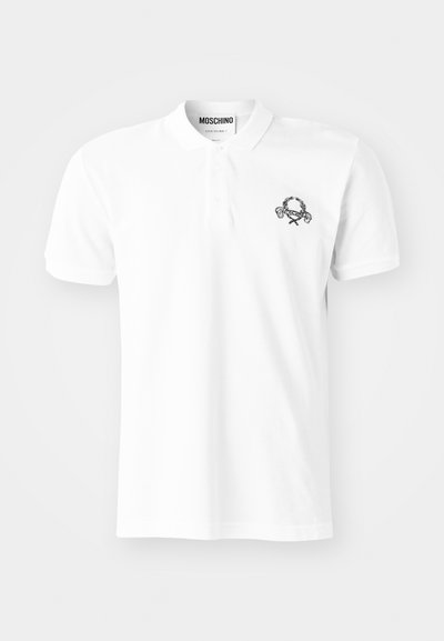 Valge puuvillane polo särg, mille vasakul rindkere kohal on must tikand. Klassikaline krae ja nööbiplokk.