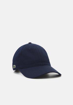 Castravete de baseball albastru marin, fabricat din bumbac, cu o margine curbă și un mic logo brodat verde pe partea stângă. Curea ajustabilă pe spate.