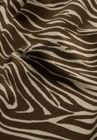 Fabric with smooth texture featuring dark brown and beige zebra-like stripes creating an animal print pattern.