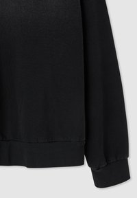 Felpa nera con una texture liscia, polsini e orlo a costine. Caratterizzata da una vestibilità leggermente ampia, senza motivi o accenti visibili.