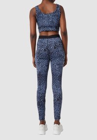 Krótki top w niebieski leopardzi wzór oraz legginsy, charakteryzujące się dopasowanym krojem i elastycznym materiałem. Akcentowane czarnym pasem w talii oraz fakturowanymi wzorami.