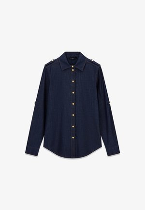 Camicia di jeans a maniche lunghe blu scuro con bottoni dorati lungo la parte anteriore e spalline con bottoni su sfondo bianco.