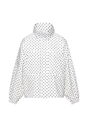 Jachetă ușoară albă cu buline negre, guler înalt, manșete elastice și buzunare frontale, prezentată pe un fundal simplu.