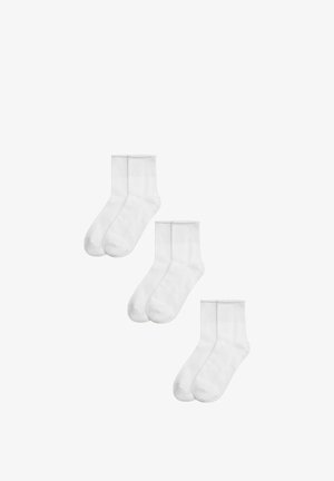 Tres pares de calcetines blancos lisos hasta el tobillo, dispuestos sobre un fondo blanco.