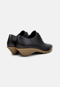 Μαύρα δερμάτινα παπούτσια με ομαλή επιφάνεια, καμπυλωτή φτέρνα και ανθεκτική λαστιχένια σόλα, με διακοσμητικό ράψιμο και σχέδιο με κορδόνια.