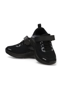 Zapatillas deportivas negras con una parte superior de malla transpirable, presentan cordones y una correa de velcro, suela texturizada y detalles reflectantes.