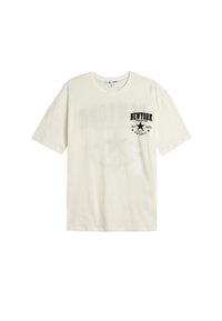 Creme kortærmet t-shirt lavet af bomuld. Har et sort trykt "NEW YORK" grafisk design på den øverste venstre side og en loose fit stil.