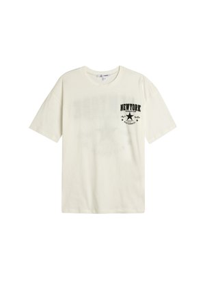 Creme kortærmet t-shirt lavet af bomuld. Har et sort trykt "NEW YORK" grafisk design på den øverste venstre side og en loose fit stil.