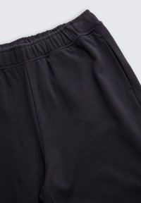 Zwarte broek met elastische tailleband van een gladde, gestructureerde stof. Kenmerken zijn onder andere een relaxte pasvorm en zijzakken voor extra functionaliteit.