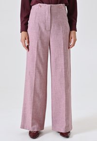 Pantaloni palazzo rosa chiaro in tessuto testurizzato, con vita piatta, due bottoni in vita e una linea plissettata per un tocco di stile in più.