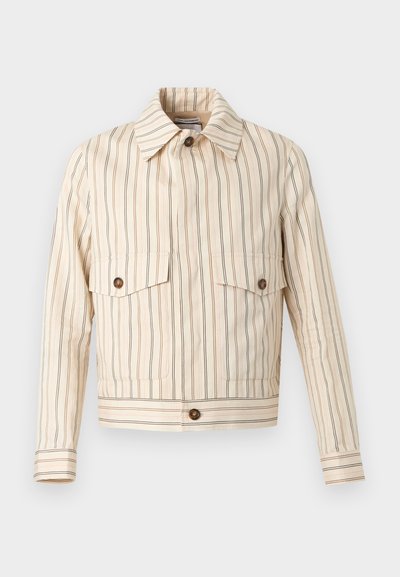 Veste courte beige avec fines rayures verticales marron, poches poitrine à rabat boutonnées, boutons marron et col pointu.