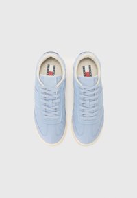 Lys blå sneakers med en glatt skinnfinish, med hvite snører, en polstret krage og en gummisåle. Subtile teksturerte detaljer på overdelen.