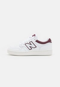 White athletic sneakers featuring a perforated toe, maroon accents, a stitched logo, and a textured rubber sole. Lace-up design.