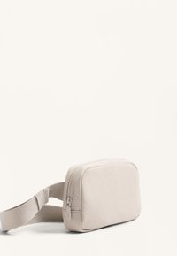 Borsa a tracolla beige con superficie liscia, forma rettangolare, chiusura con zip e tracolla regolabile per un indosso sicuro.