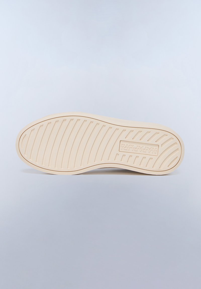 Suela de zapato en color crema con surcos texturizados y un logotipo. Material de goma suave diseñado para ofrecer agarre y durabilidad.