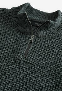 Pulover zip-neck de culoare gri închis, cu un model de tricot texturat, guler ribbed și fermoar metalic. Materialul pare grozav și călduros.