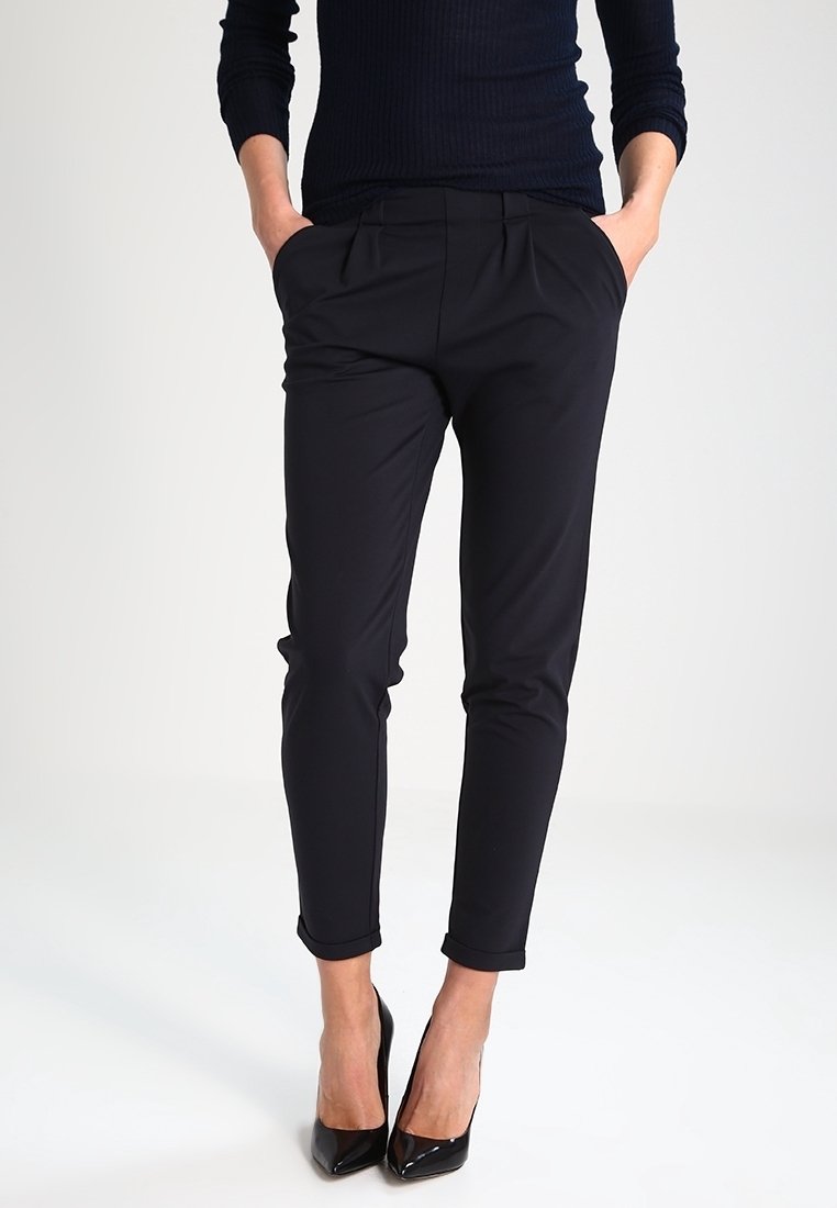 Pantalon noir ajusté à coupe slim, avec un devant plat, deux poches latérales et des revers roulés. Le tissu semble lisse et léger.