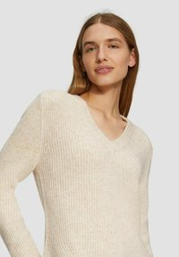 Elfenbeinfarbener Strickpullover mit V-Ausschnitt, langen Ärmeln, strukturiertem Stoff und subtilen Farbvariationen. Entworfen für eine körperbetonte Passform.