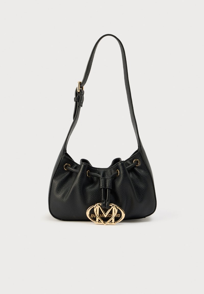 Μαύρη δερμάτινη τσάντα με στρογγυλεμένο σχήμα, κλείσιμο με κορδόνι και χρυσή διακριτική λεπτομέρεια λογότυπου. Λείο υλικό με λεπτή υφή κόκκων.