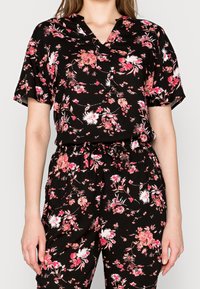 Black floral print two-piece outfit featuring short sleeves, a v-neck top, and elastic waistband pants with a drawstring detail.