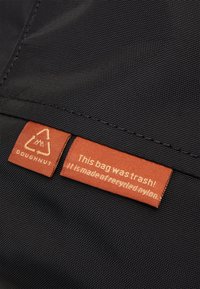 Black nylon bag featuring a textured surface and two rectangular tags in orange, one with a recycling symbol and a message about sustainable materials.