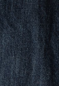 Tela de mezclilla azul oscuro con una textura suave, que presenta sutiles manchas claras y un patrón de tejido clásico en toda su extensión.