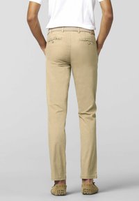 Beige chinos with a streamlined fit, featuring back pockets and a woven belt. The fabric has a smooth texture, ideal for casual wear.