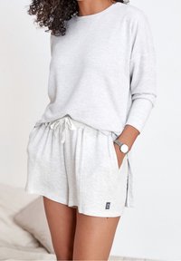 Lys grå tekstureret langærmet top og matchende shorts med snøre, der har sidelommer og logo detaljer. Materialet er en bomuldsblanding.